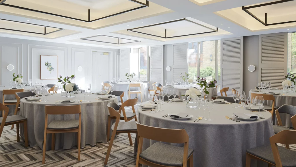 Luxury banquet room with coffered ceiling illuminated by linear LED strips, round tables with gray linens, wooden chairs, floral centerpieces, and large windows