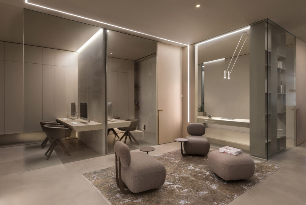 Elegant modern office interior with linear LED lighting along ceiling and walls, glass partitions, curved beige furniture, floating desk, and soft ambient glow