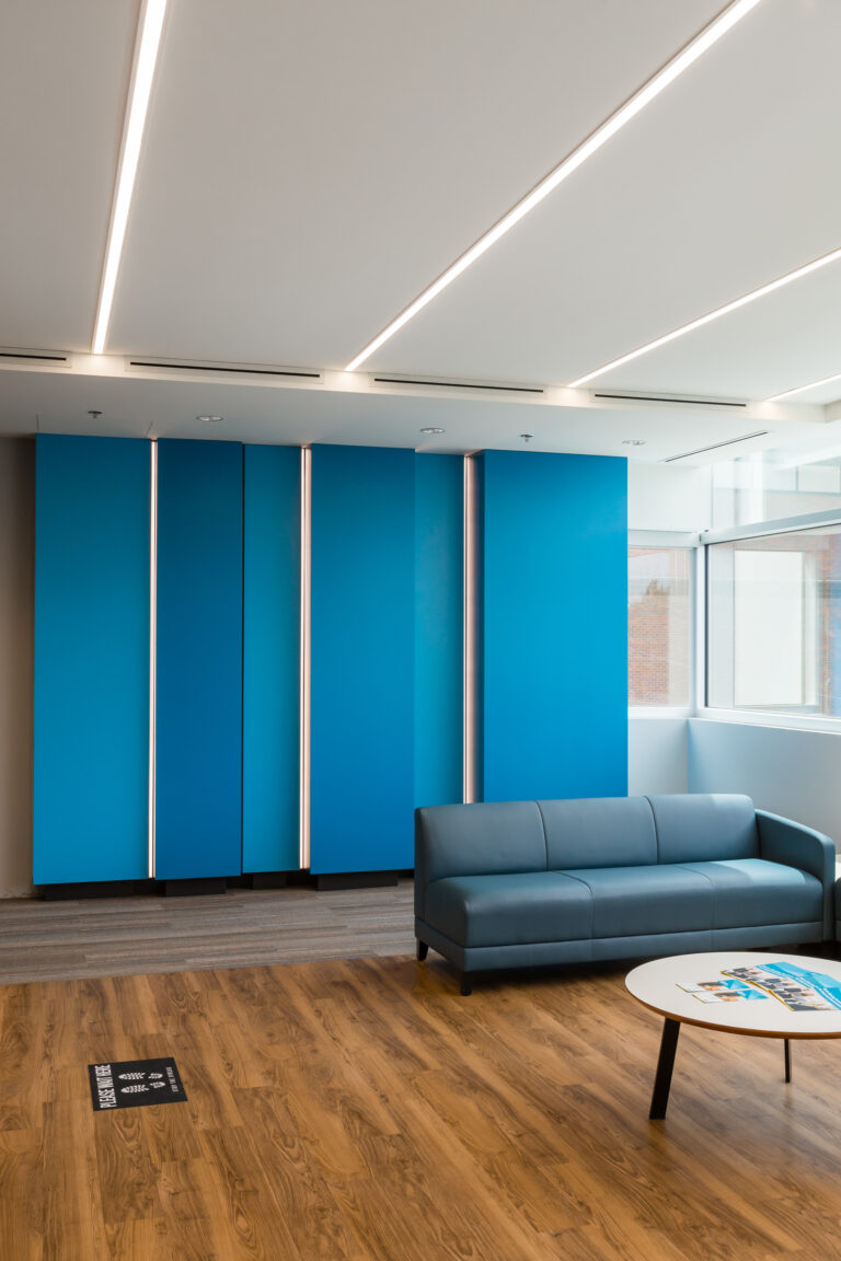 Linear LED architectural lighting with cove accents on blue panels in modern commercial office lounge Canada